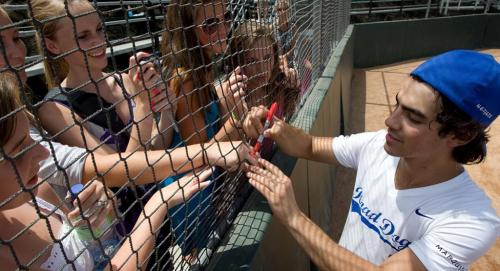 A celebrity signs autographs through a net