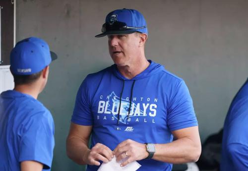 A baseball coach talks to another coach