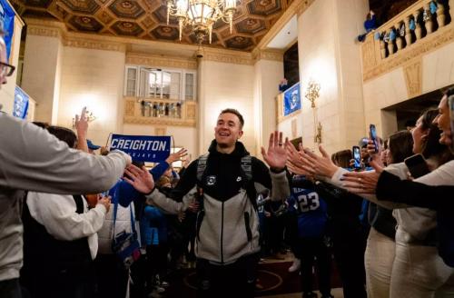 A Creighton basketball player high-fives with fans as he leaves the team hotel