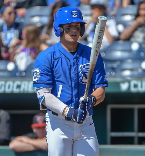 A baseball player looks at his bat