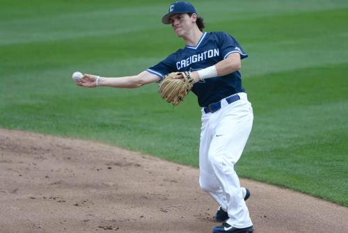 A baseball player throws the ball on the infield