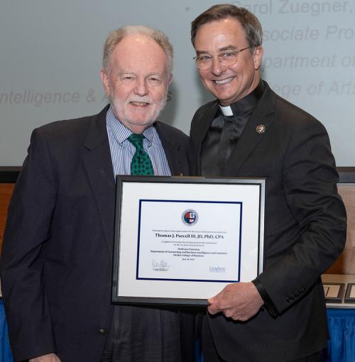 Two men pose for a photo while one holds an award