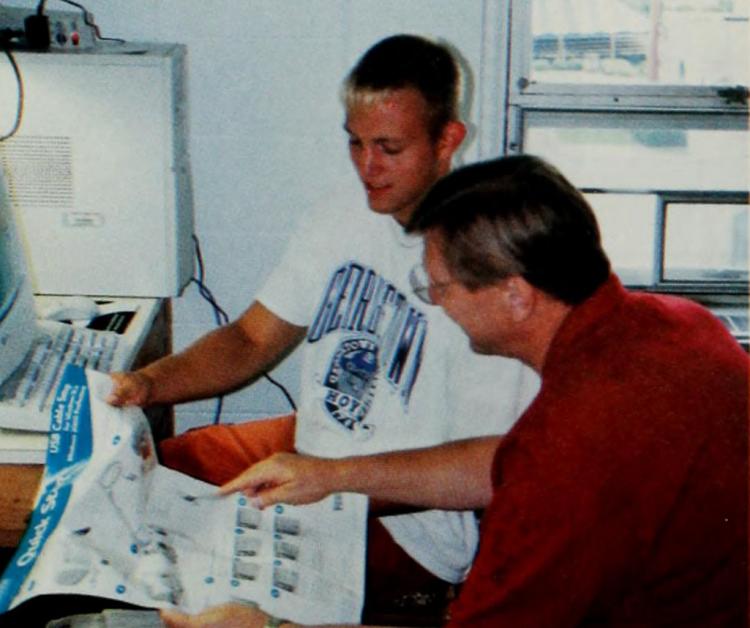 A student works with his dad to install a computer