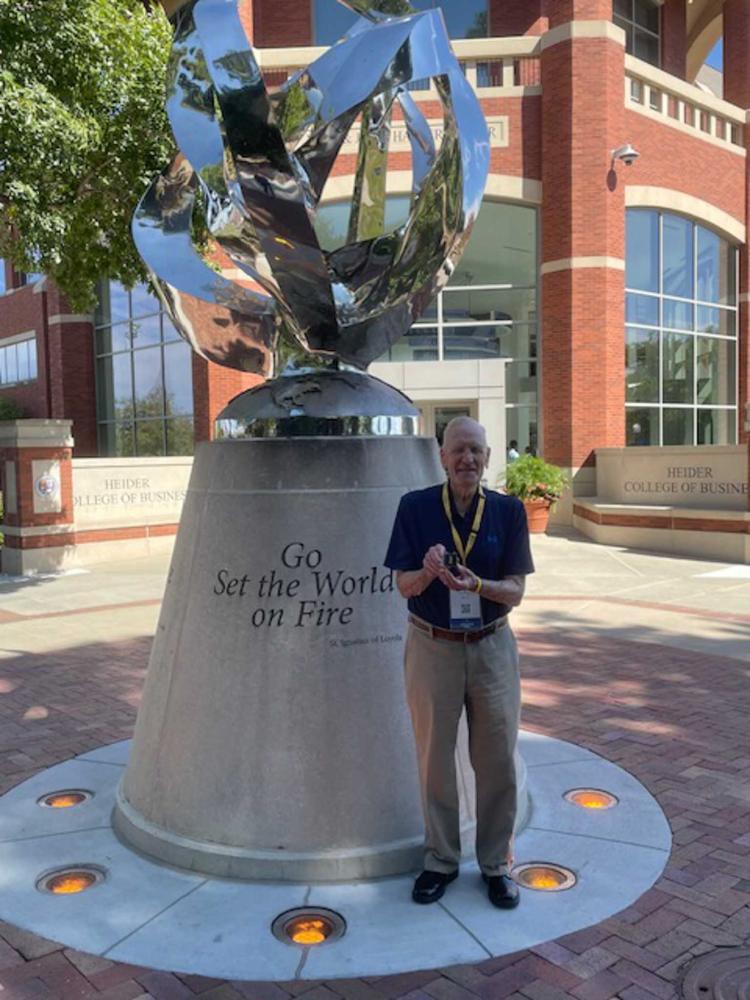 A man stands next to Creighton's Flame statue