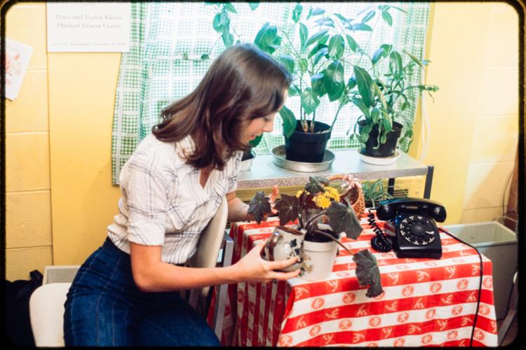 Woman waters her plant inside a Kiewit Hall dorm 