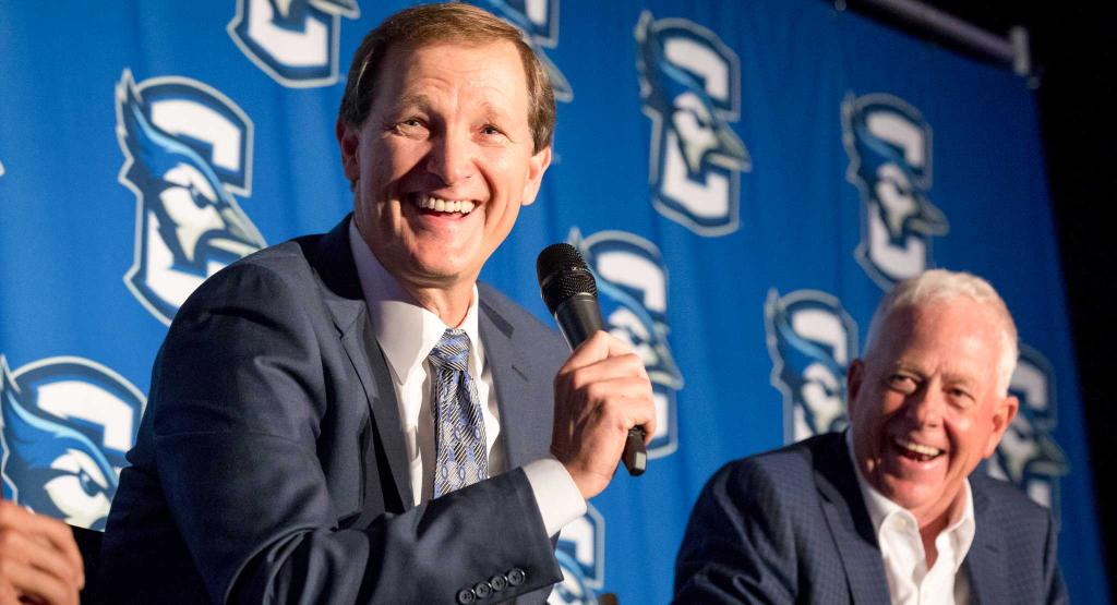 Two men smiling while speaking on a panel