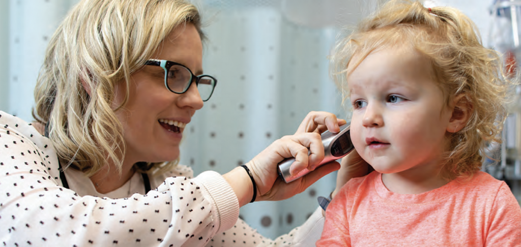 A nurse looks into a child's ear during a checkup.