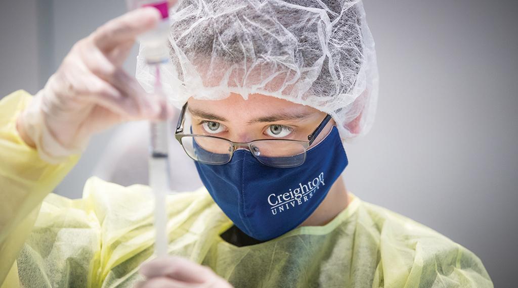 Student wearing PPE works in the pharmacy lab