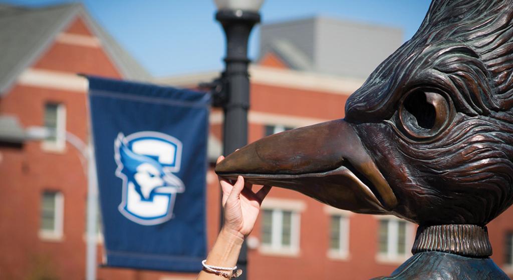 A student touches the beak of the Billy Bluejay statue