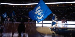 Mascot Billy Bluejay caries a Creighton flag while running on the court