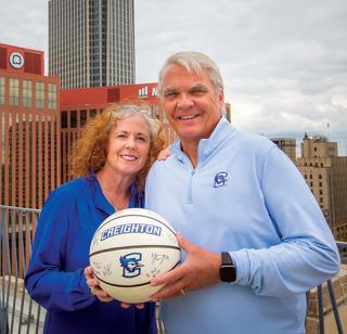 Creighton alum who support the champions circle smiling and holding a Creighton University basketball