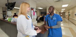 A doctor and a nurse speaking on the hospital floor.