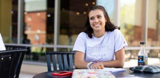 A student sitting outside, smiling.