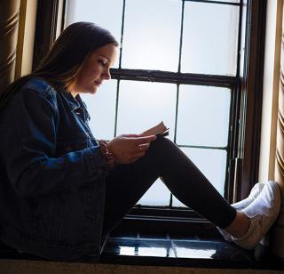 female student studying in window ledge