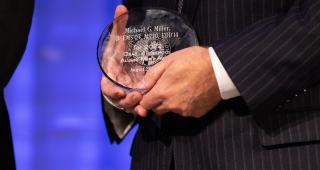 Image of man holding the Alumni Merit Award