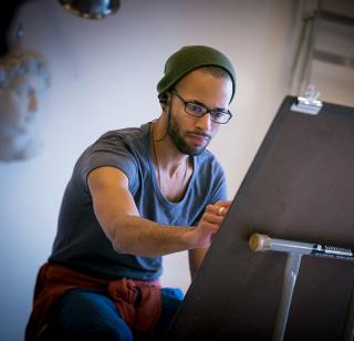 Male student draws at an easel