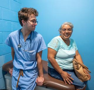 School of Medicine student sits next to patient