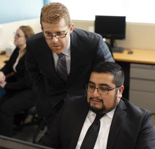 Male School of Law faculty member looks over shoulder of male law student