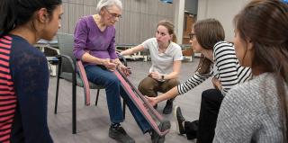 Students work with a patient on physical therapy.