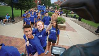 Students touch the beak of the Billy Billy statue on campus.