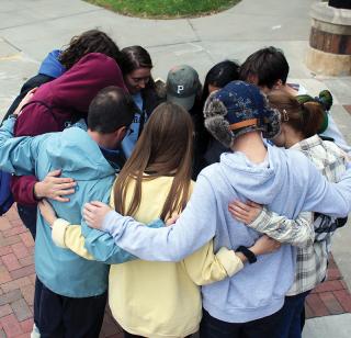 A group of Creighton students huddle together in prayer.