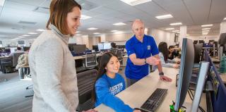 Student working on computer with guidance of faculty