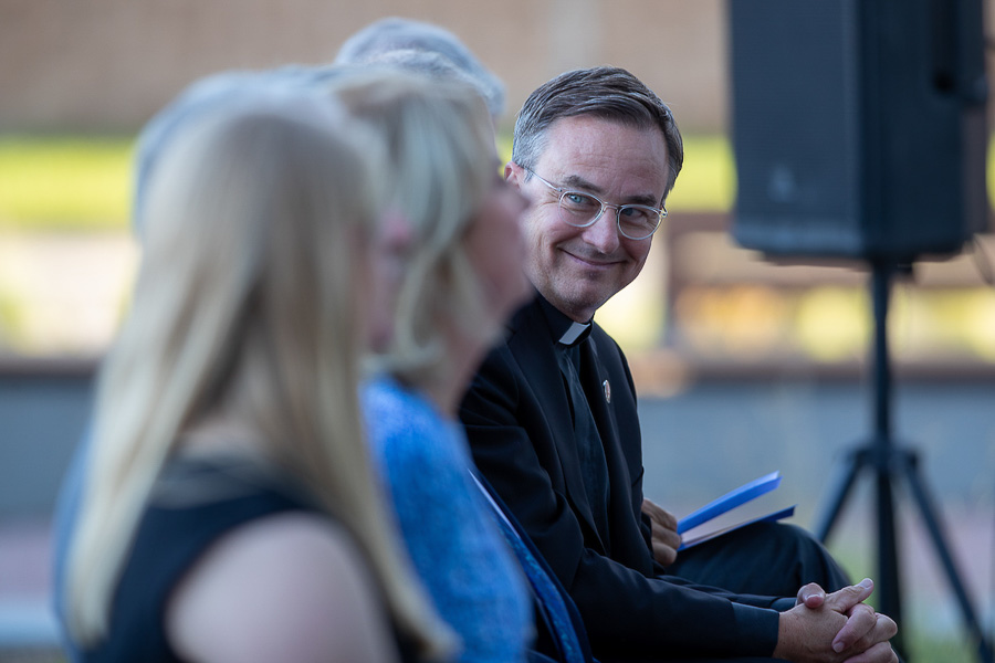 Father Hendrickson sitting with the audience at the CL and Rachel Werner Center dedication event.